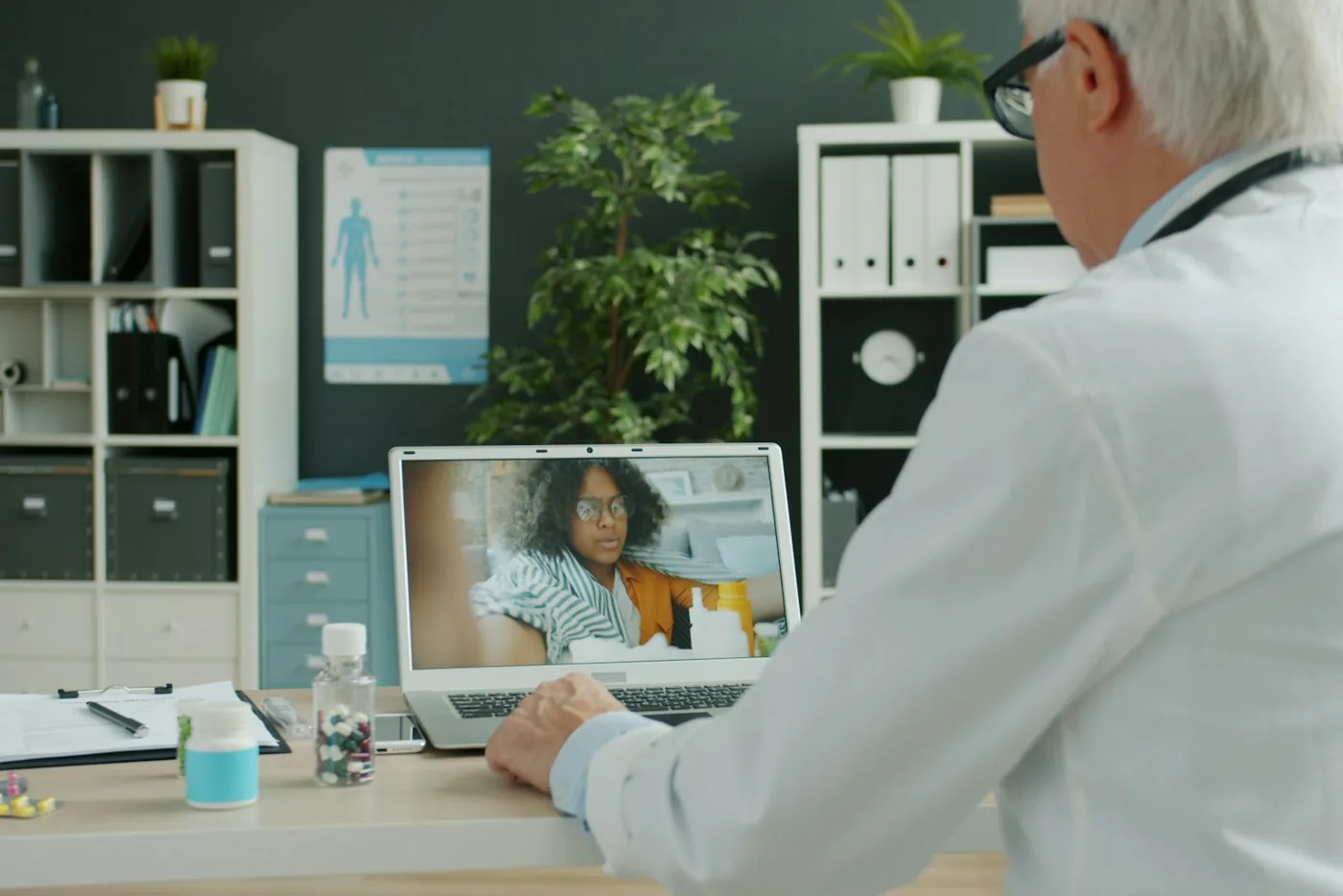 A patient at home on a video consultation, with the doctor on the laptop screen